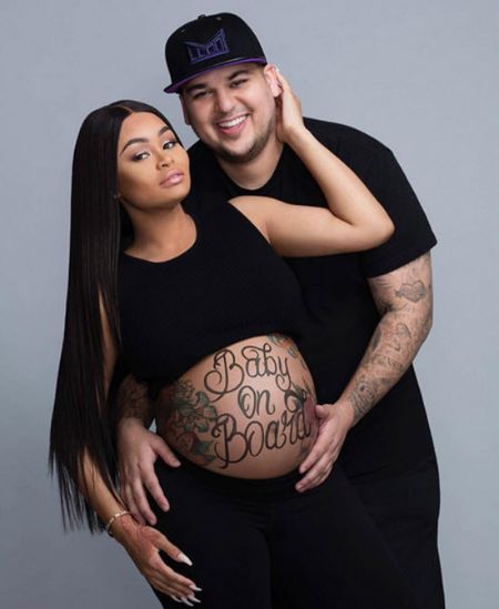 chyna pregnant and rob standing behind holding her with both hands with chyna's hand on his neck 